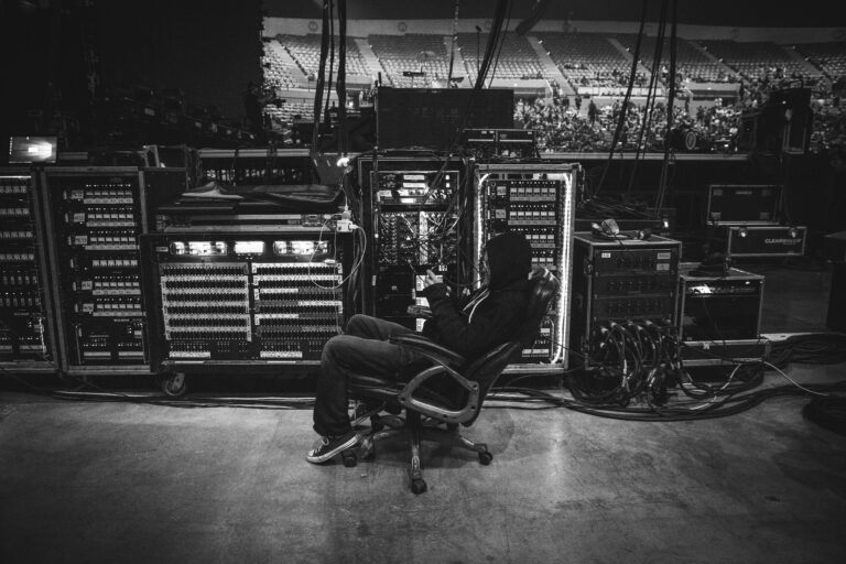Backstage technician seated beside audio equipment before a live concert