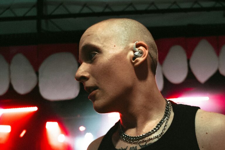 Concert performer wearing in-ear monitors backstage under red stage lights