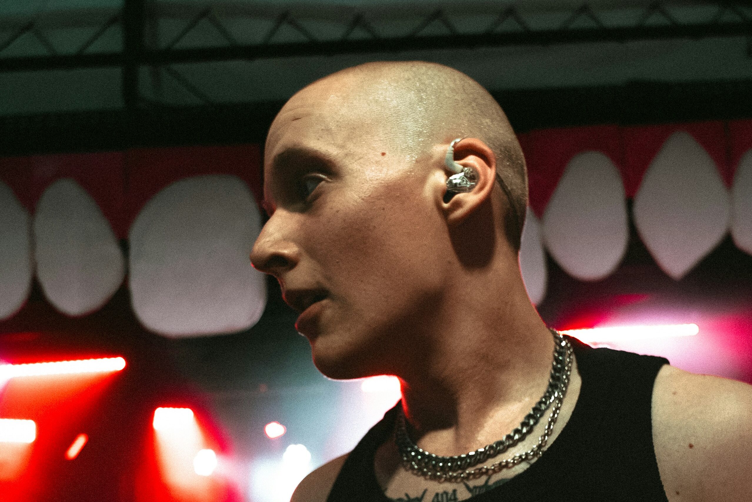 Concert performer wearing in-ear monitors backstage under red stage lights