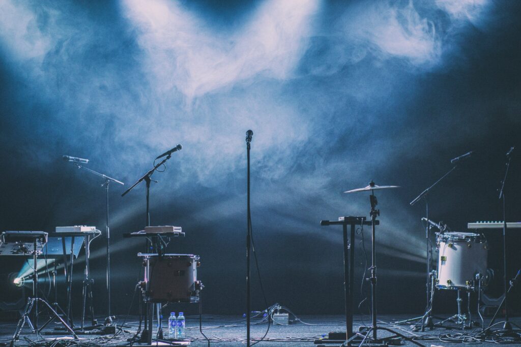 Empty concert stage with microphones, drums and blue stage smoke before a performance