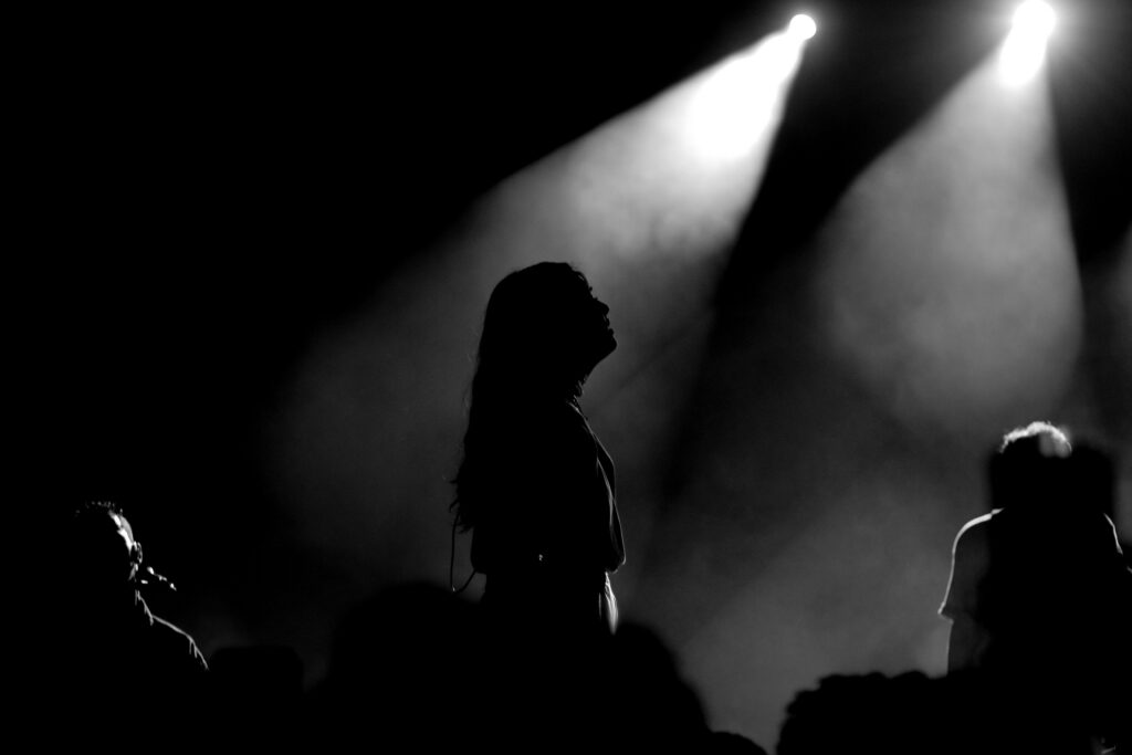Silhouetted performer on stage under dramatic black-and-white spotlights