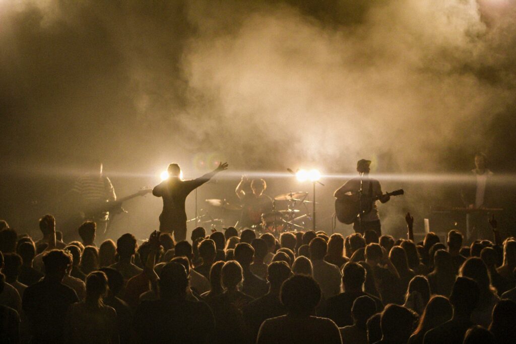 Band performing live on stage in front of a concert crowd.